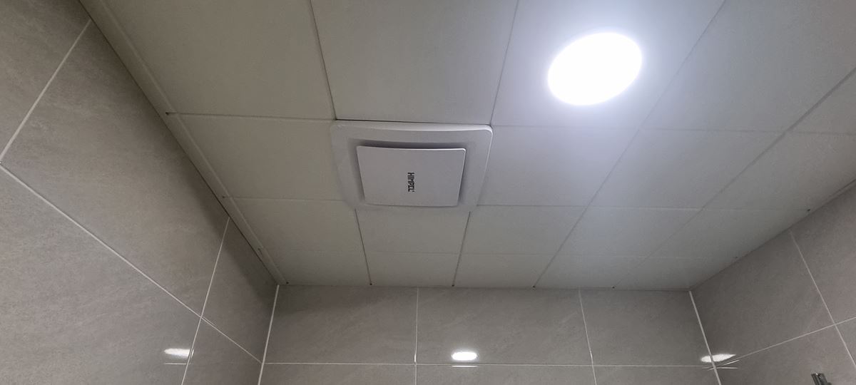 회색 타일 벽 위 흰 천장에 다시 단 사각 디퓨저와 둥근 LED 조명