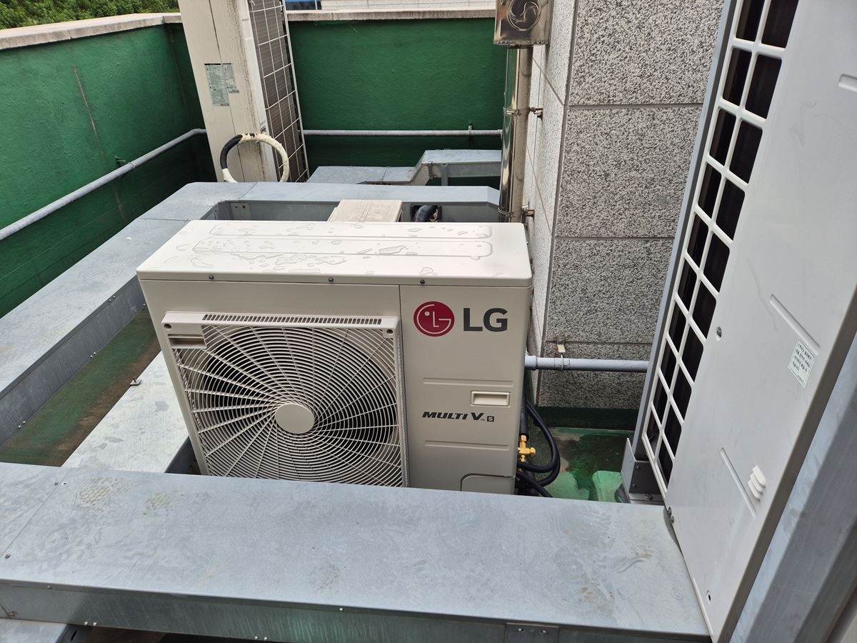 건물 바깥 철제 받침 위에 놓인 흰색 실외기와 옆의 다른 실외기들