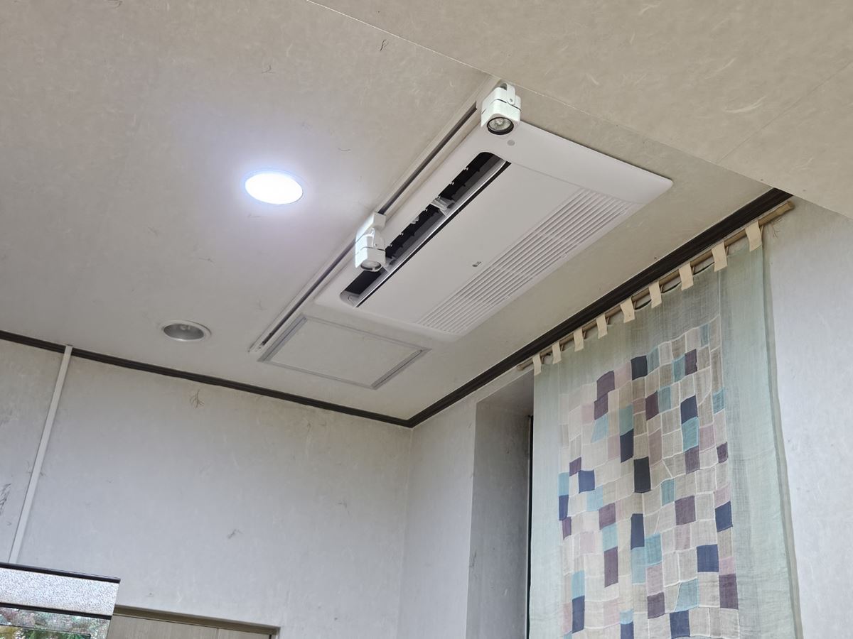 한지 무늬 천장에 조명 레일과 나란히 자리한 흰색 1방향 실내기와 아래쪽 벽의 천 걸개